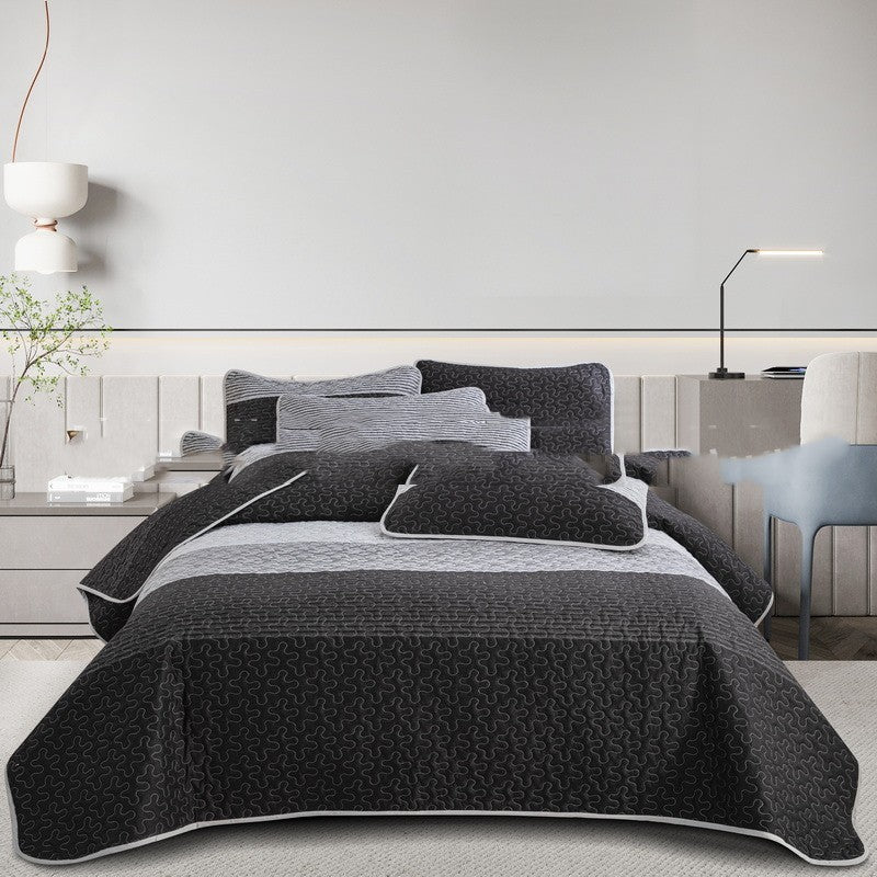 Gray quilt set on a bed in a modern bedroom setting