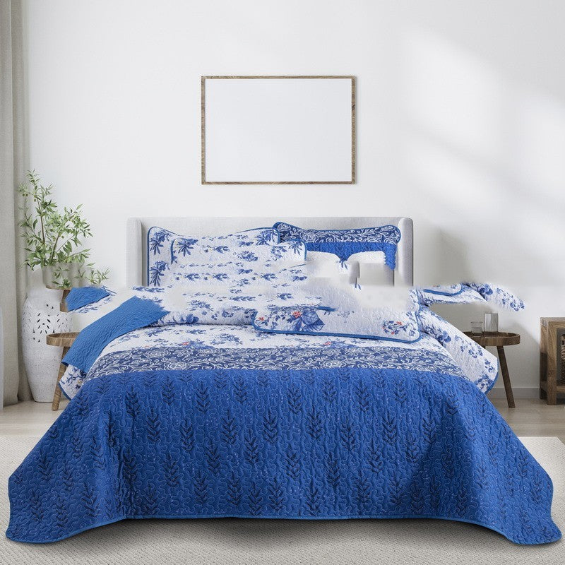 Blue and white floral bedspread on a bed in a bedroom setting.