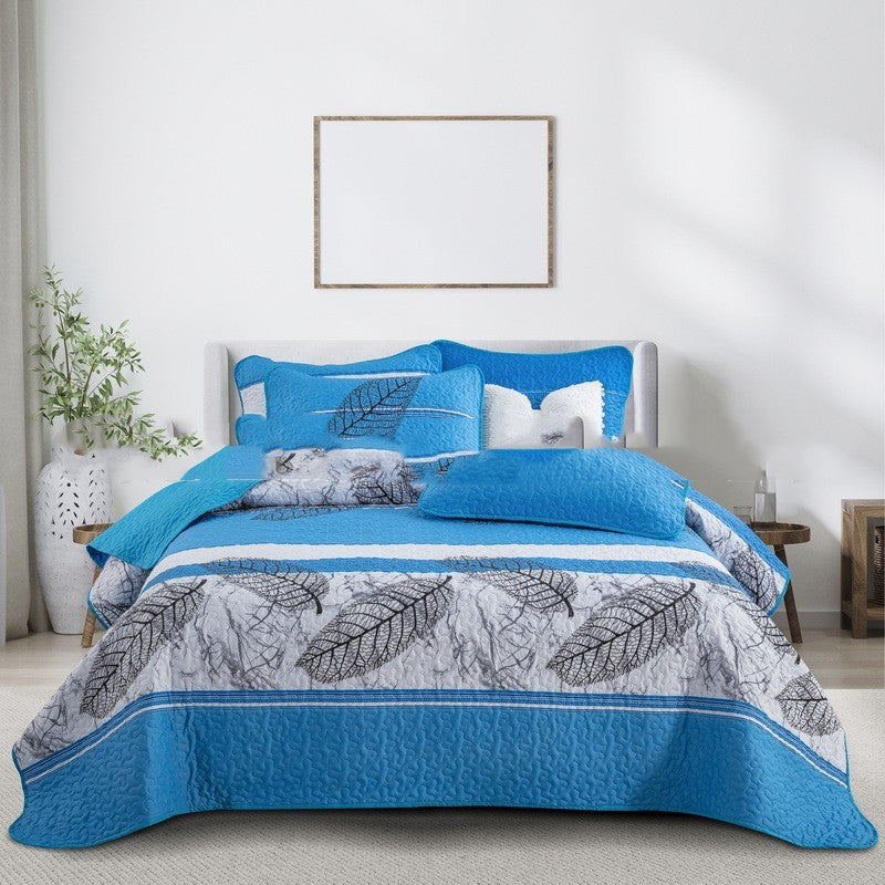 Blue and gray leaf-patterned comforter set on a bed in a bedroom.