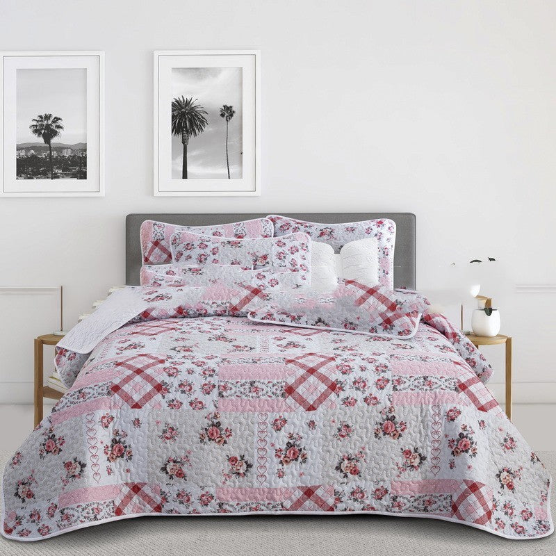 Floral quilt spreads set on a bed with matching pillows